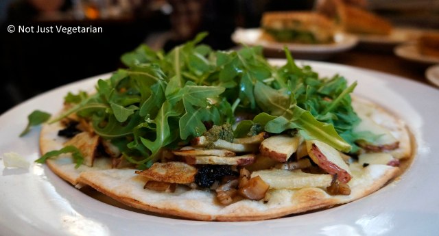 Vegan roasted potato pizza with sauteed mushrooms, arugula, oil cured black olives, and pesto at Peacefood Cafe NYC